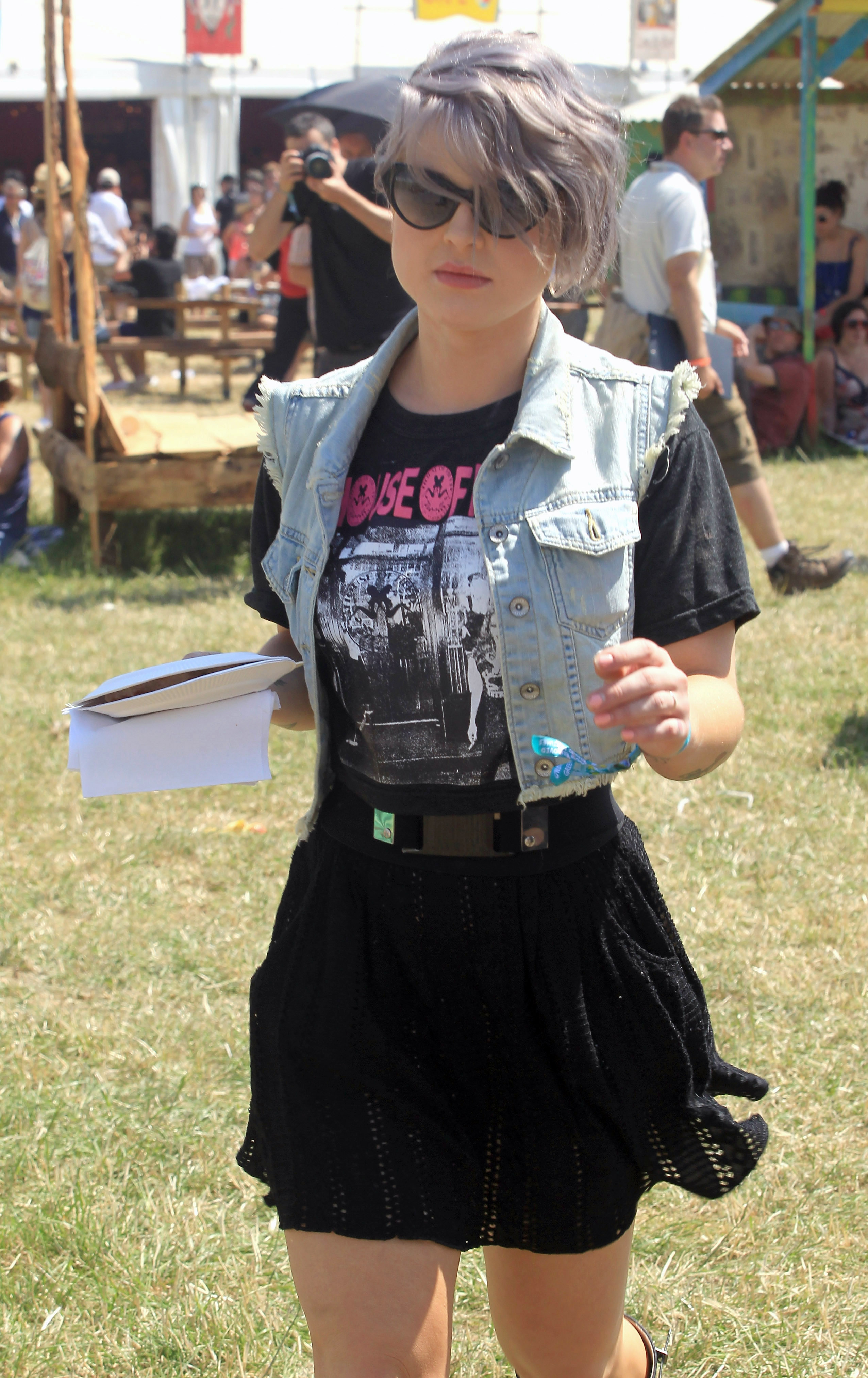Kelly Osbourne matchar sitt lavendelfärgade hår med jeansväst på festival.